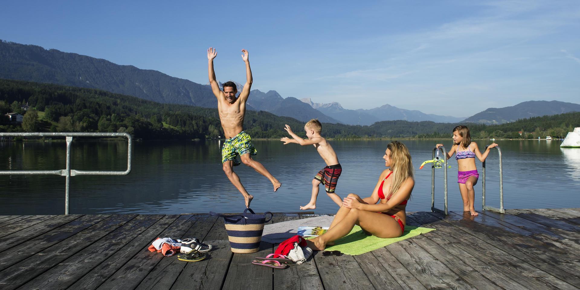 Alpen Adria Hotel & Spa in Presseggersee – Familie springt in den Pressegger See mit Bergpanorama | Wellnesshotel Kärnten