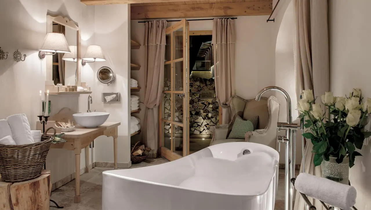 Luxuriöses Badezimmer mit freistehender Badewanne und Blick auf Holzstapel im INNs HOLZ Chaletdorf.