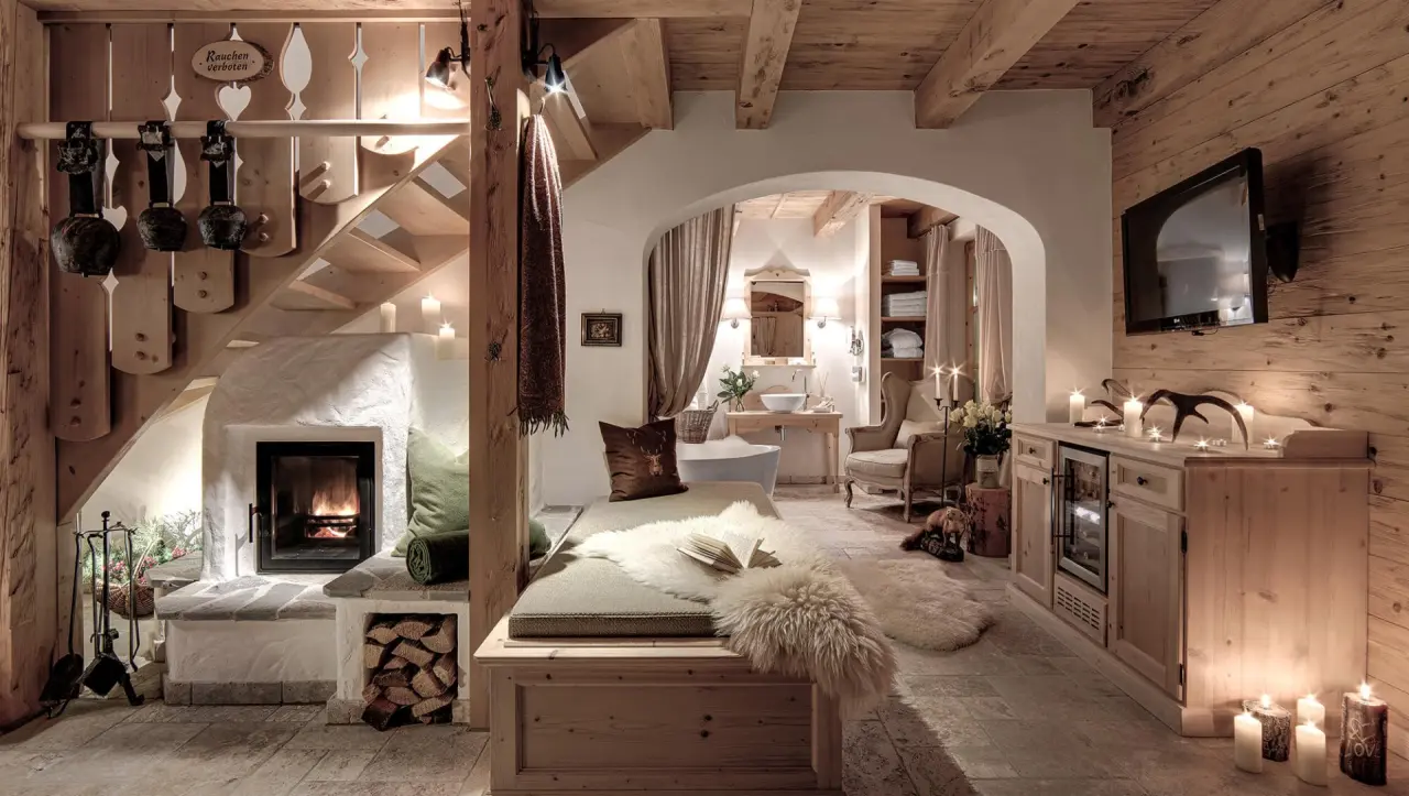 Gemütliches Chalet-Interieur im INNs HOLZ Chaletdorf mit Kamin, Kuschelecke und freistehender Badewanne für entspannte Stunden.