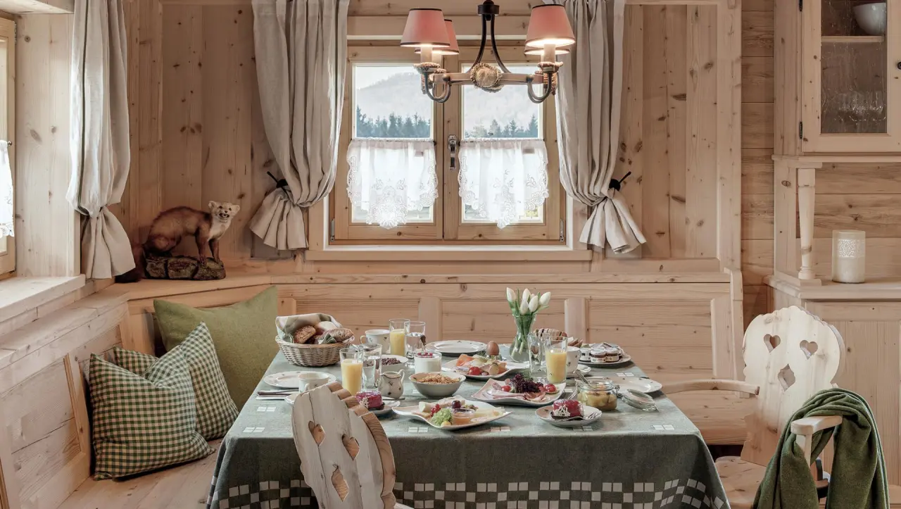 Reichhaltiges Frühstück am rustikalen Holztisch im Chalet des INNs HOLZ Chaletdorf mit Blick auf die Natur.