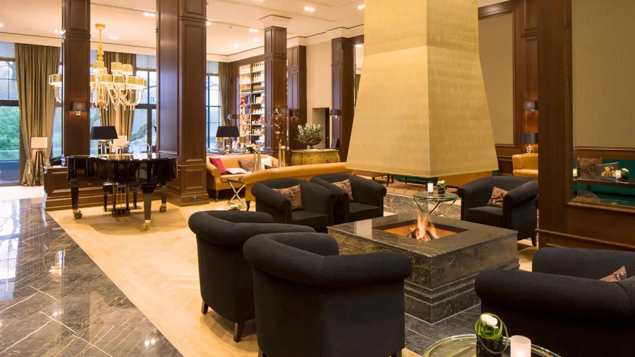 Elegante Hotellobby mit Kamin, Flügel und luxuriösen Sitzbereichen im Kempinski Hotel Frankfurt Gravenbruch.