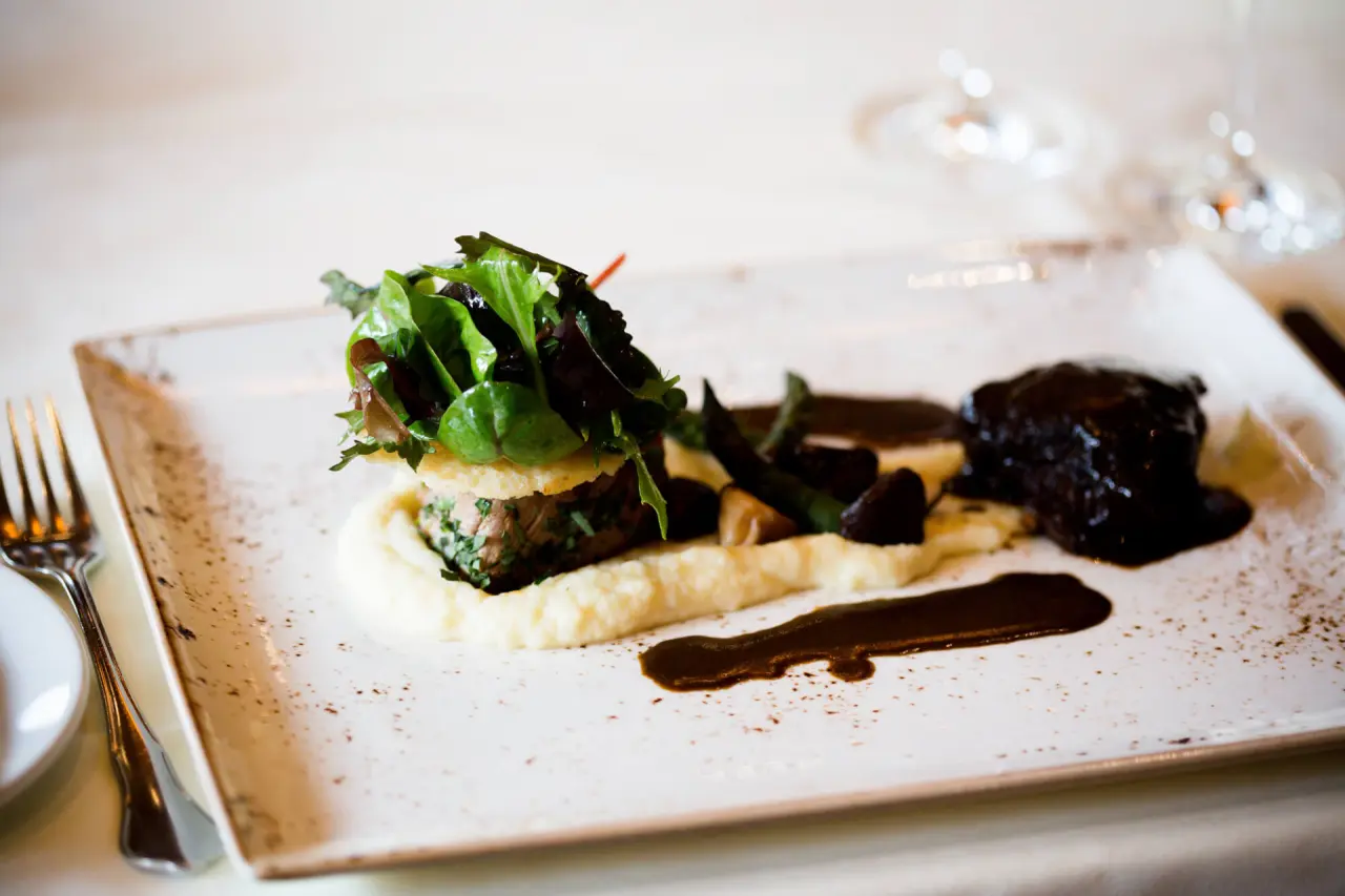 Fein angerichtetes Gericht mit Fleisch, Püree und Salat im Restaurant des Hotel Bayerwaldhof.