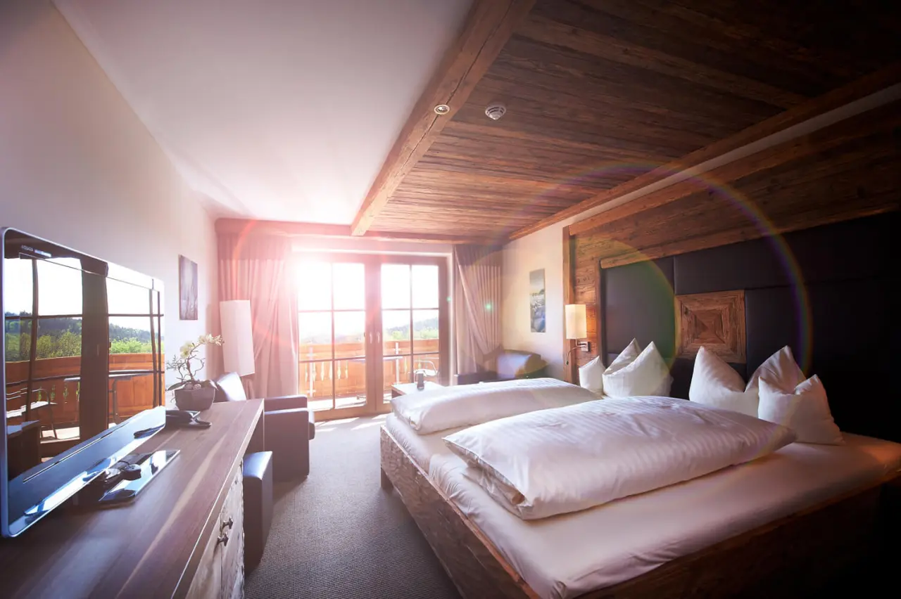 Gemütliches Doppelzimmer im Bayerwaldhof mit Holzelementen, Balkon und Blick ins Grüne für entspannte Aufenthalte.