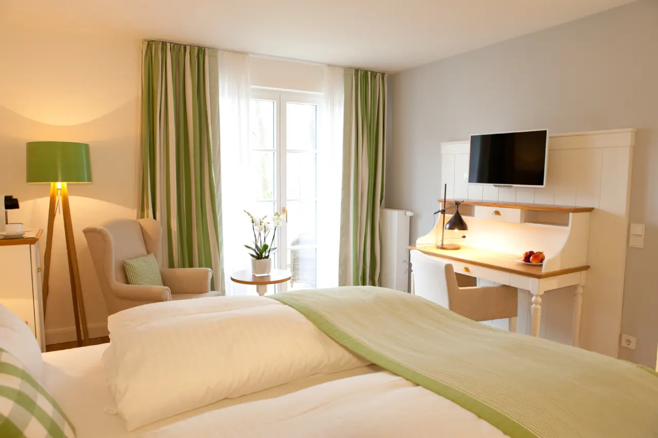 Gemütliches Hotelzimmer im Fuchsbau Romantik Hotel mit Doppelbett, Schreibtisch und Balkonzugang.