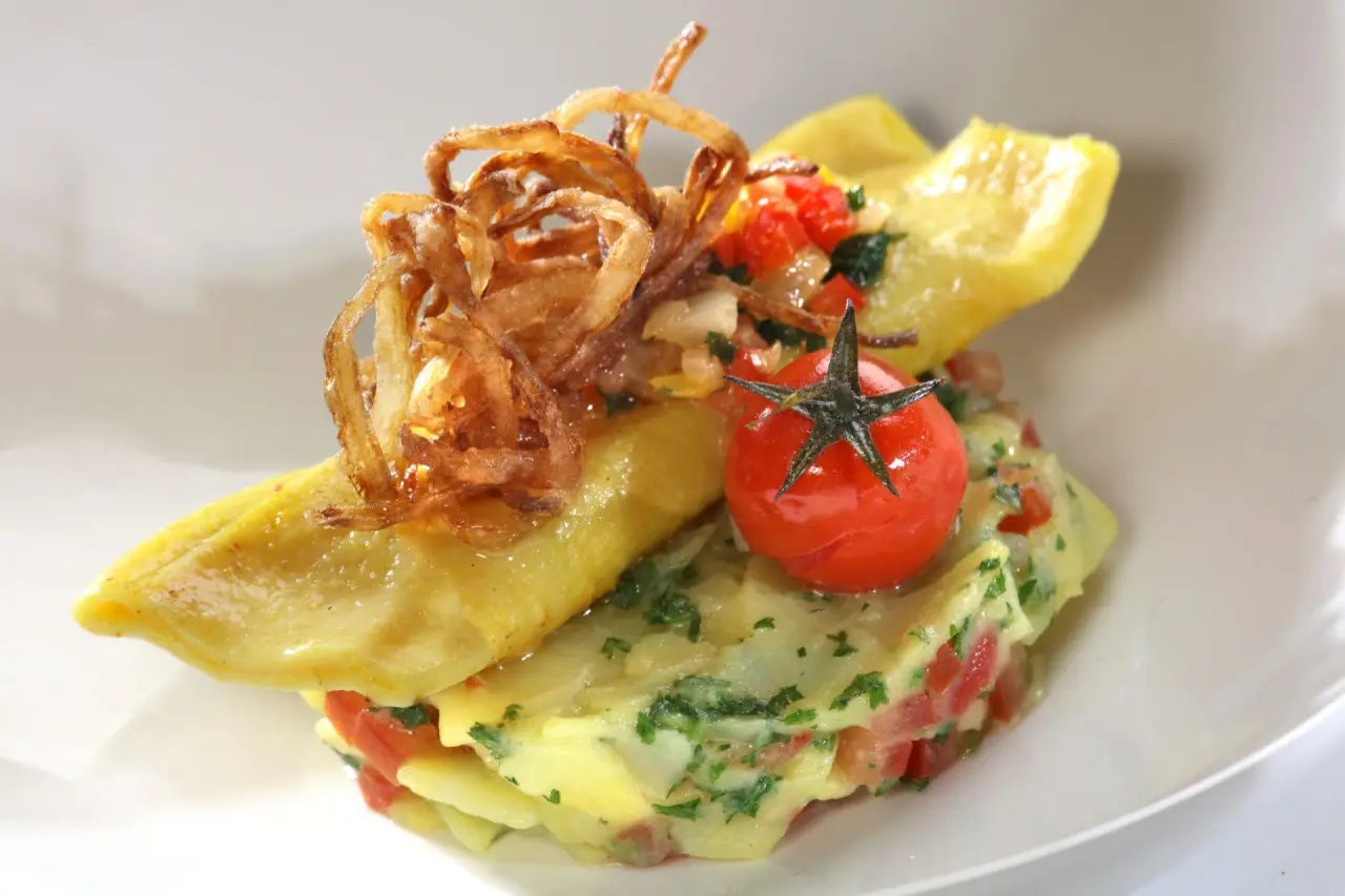 Kreativ angerichtetes Gericht mit Maultasche, Tomate und Röstzwiebeln im Restaurant des Hotel Thomahof.