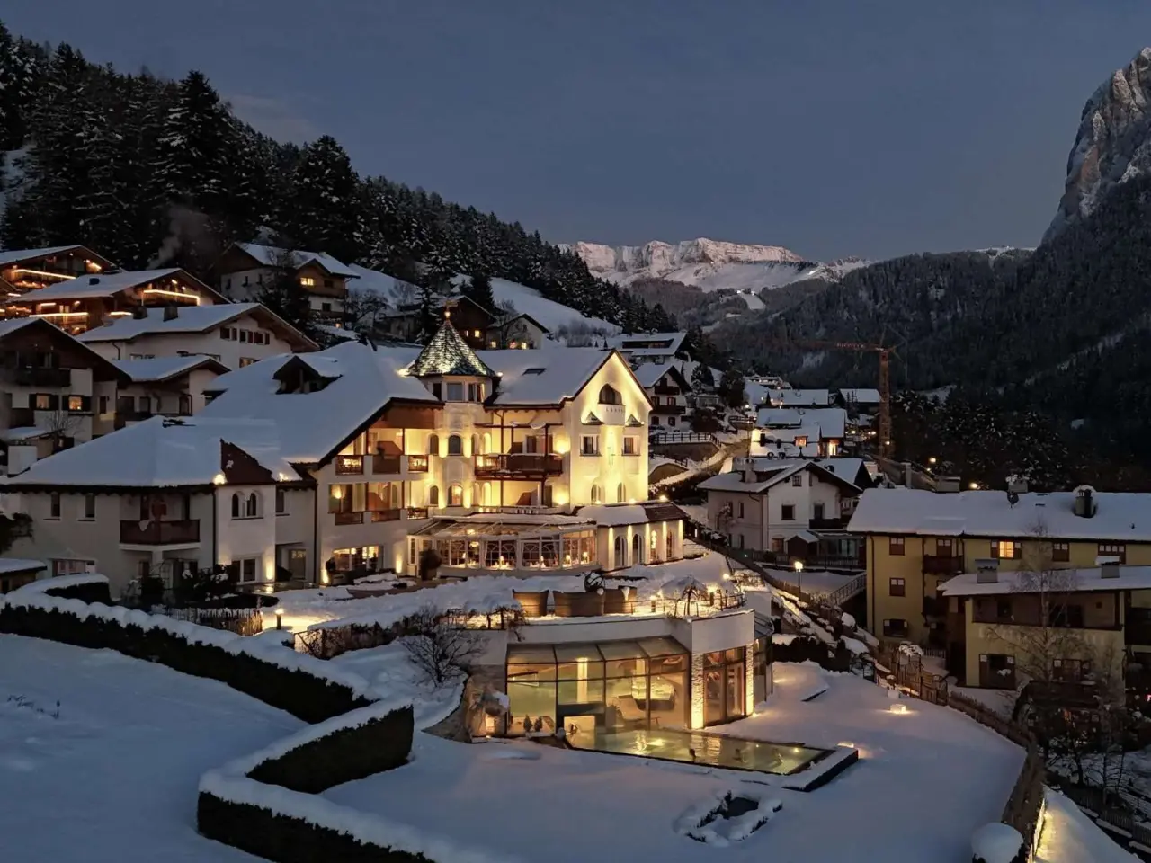 Alpenheim Charming Hotel & Spa in St. Ulrich – Beleuchtete Außenansicht mit Pool im Winter | Wellnesshotel Dolomiten