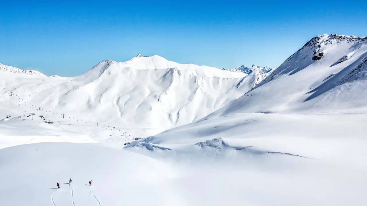 Verschneite Alpenlandschaft mit Skifahrern und Liftanlagen in Serfaus. Wintererlebnis nahe Hotel DreiSonnen Serfaus.