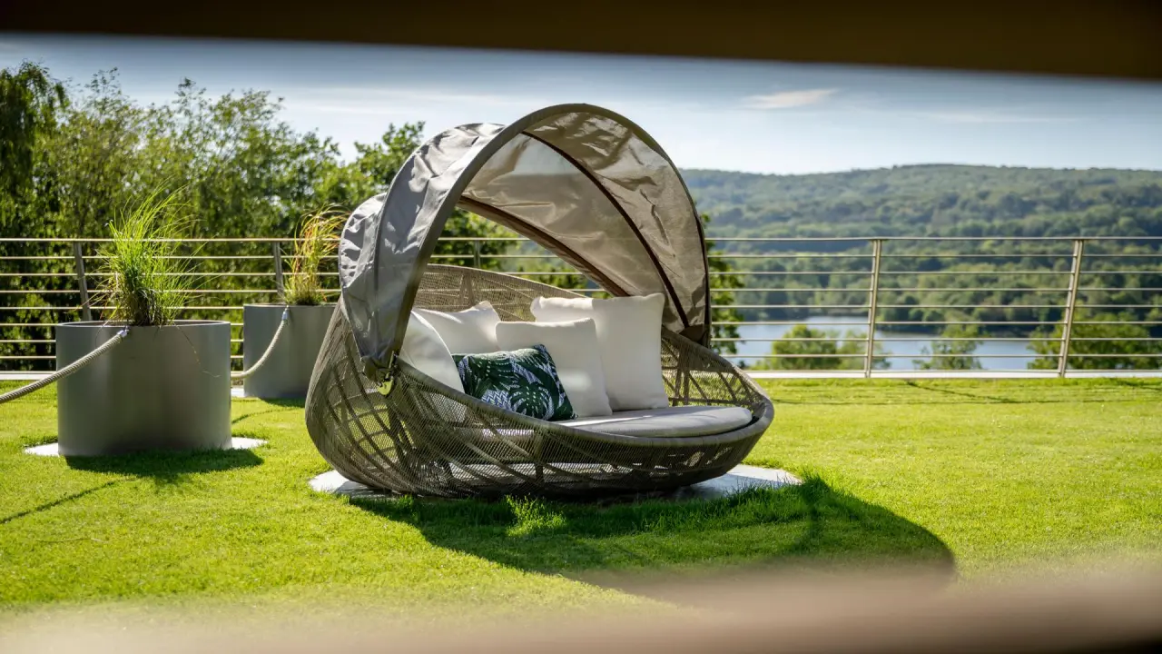 Gemütliche Outdoor-Lounge-Liege auf der Wiese mit Blick auf den See und Wald im Seezeitlodge Hotel.