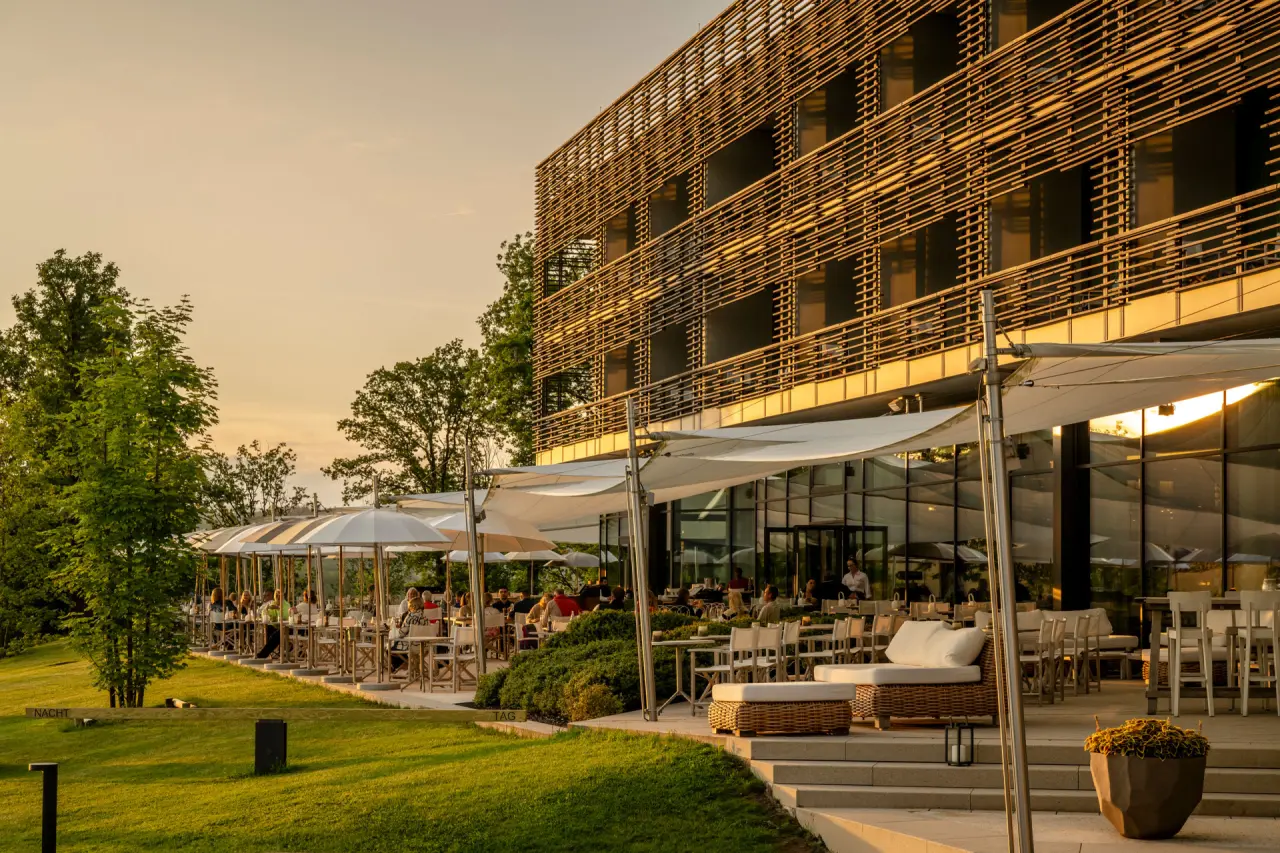 Abendstimmung auf der Restaurant-Terrasse der Seezeitlodge Hotel & Spa. Gäste genießen den Sonnenuntergang.