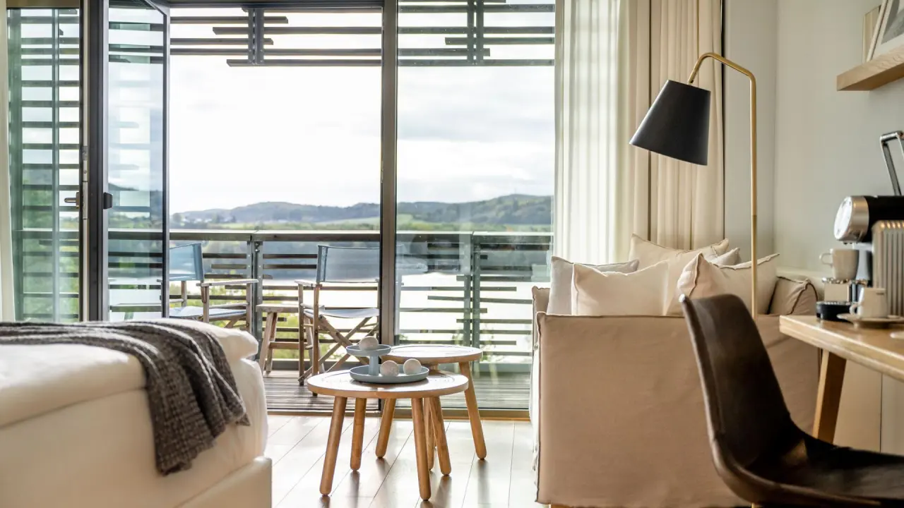 Helles Hotelzimmer mit Balkon und Seeblick im Seezeitlodge Hotel
