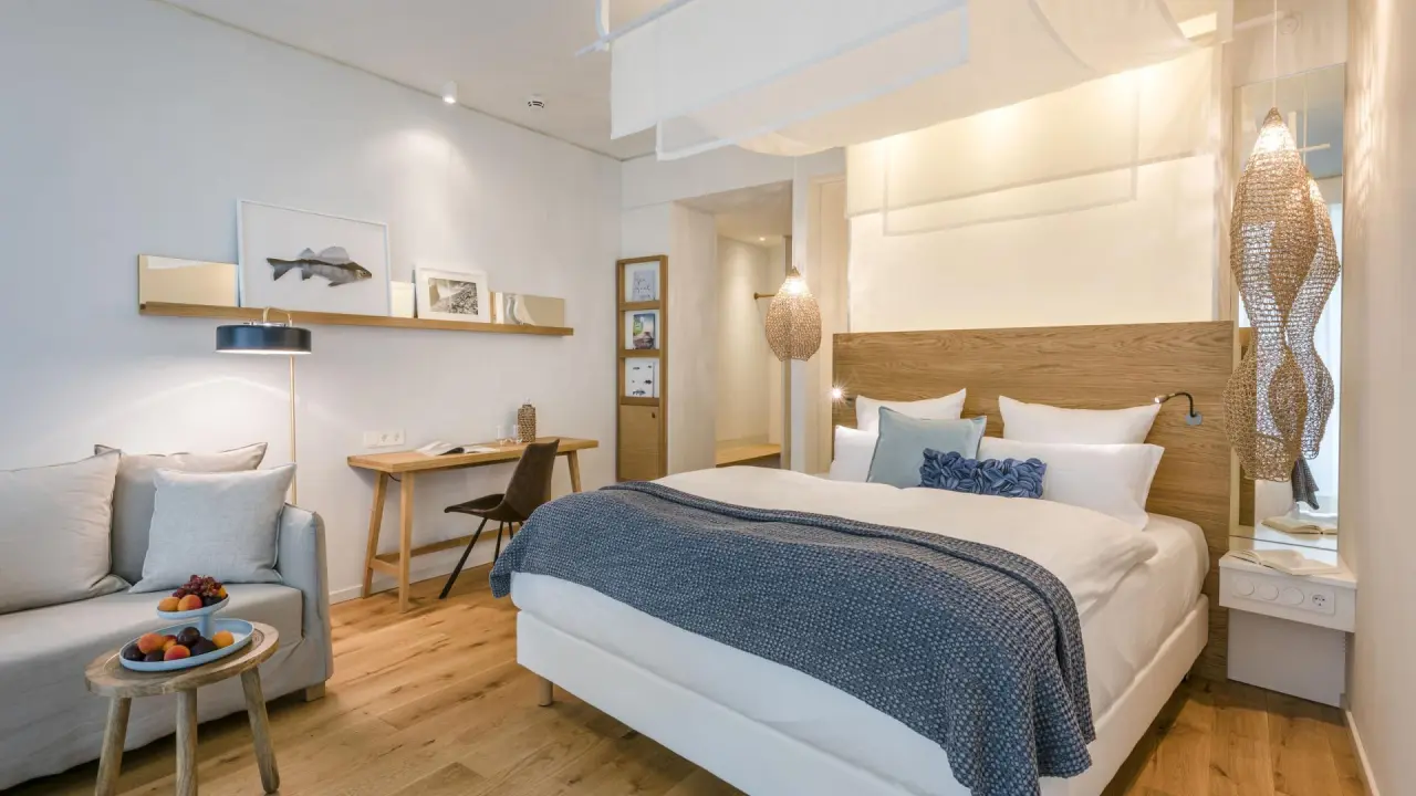 Helles, modern eingerichtetes Hotelzimmer mit Doppelbett, Sofa und Schreibtisch im Seezeitlodge Hotel.