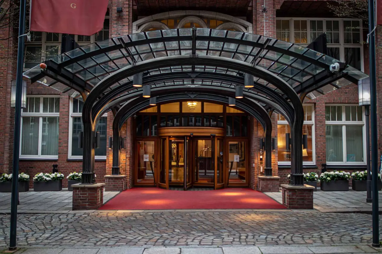 Eleganter Eingangsbereich des Park Hyatt Hamburg mit rotem Teppich und markanter Glasüberdachung.
