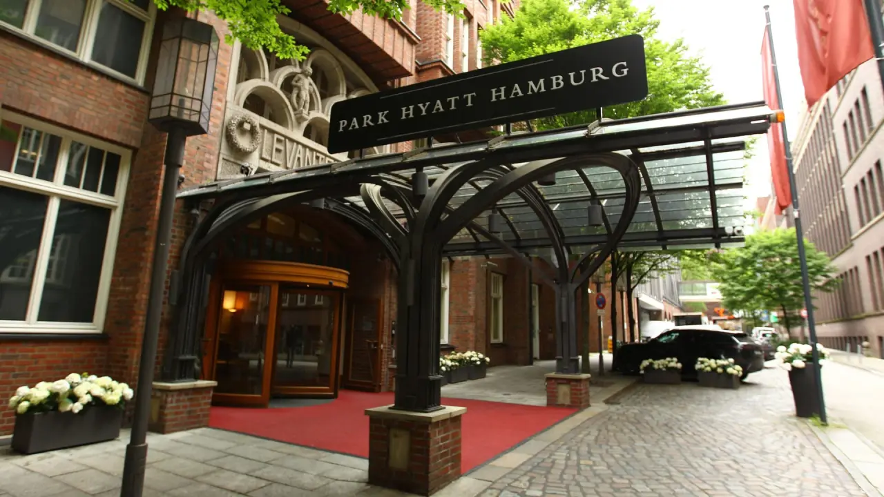 Eingangsbereich des Park Hyatt Hamburg mit elegantem Vordach, rotem Teppich und historischer Fassade.