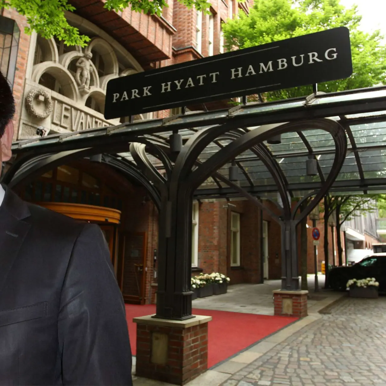 Eingangsbereich des Park Hyatt Hamburg mit Vordach, rotem Teppich und Hotel-Schild.
