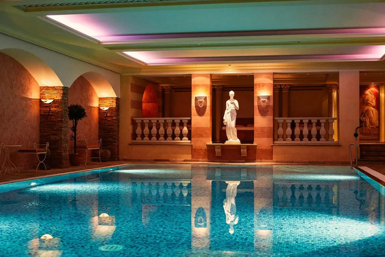 Grosszügiger Innenpool mit römischer Architektur und stimmungsvoller Beleuchtung im Hotel Engel Obertal.