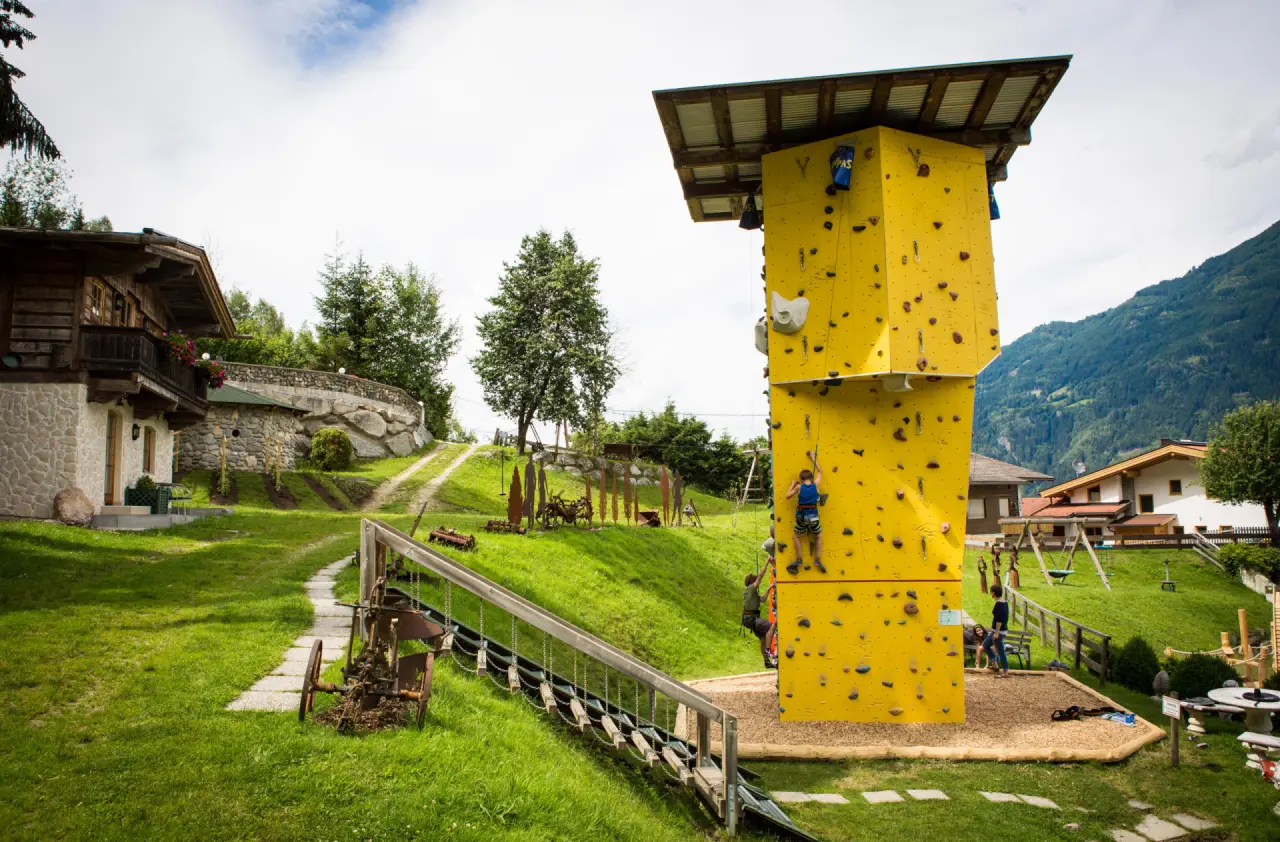 Kletterturm und Spielplatz im Aussenbereich des Alpin Family Resort Seetal****s für Familienaktivitäten.