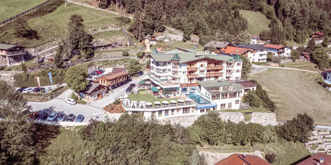 Luftaufnahme des Alpin Family Resort Seetal mit Hotelanlage, Aussenpool und grüner Berglandschaft.