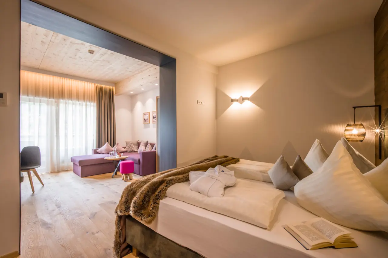 Gemütliches Hotelzimmer mit Doppelbett, Lounge-Bereich und Holzboden im Alpin Family Resort Seetal****s.