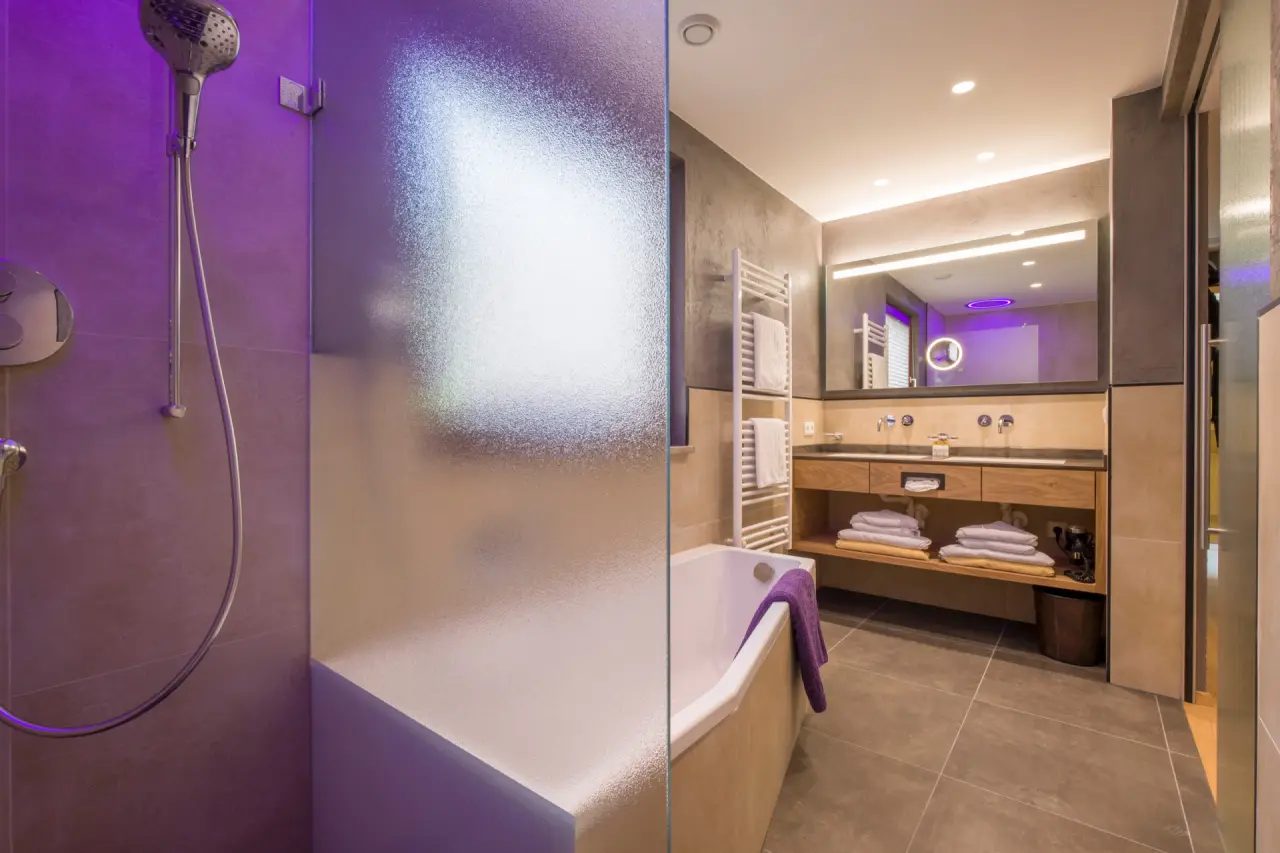 Modernes Badezimmer mit Dusche, Badewanne und Doppelwaschbecken im Alpin Family Resort Seetal****s.