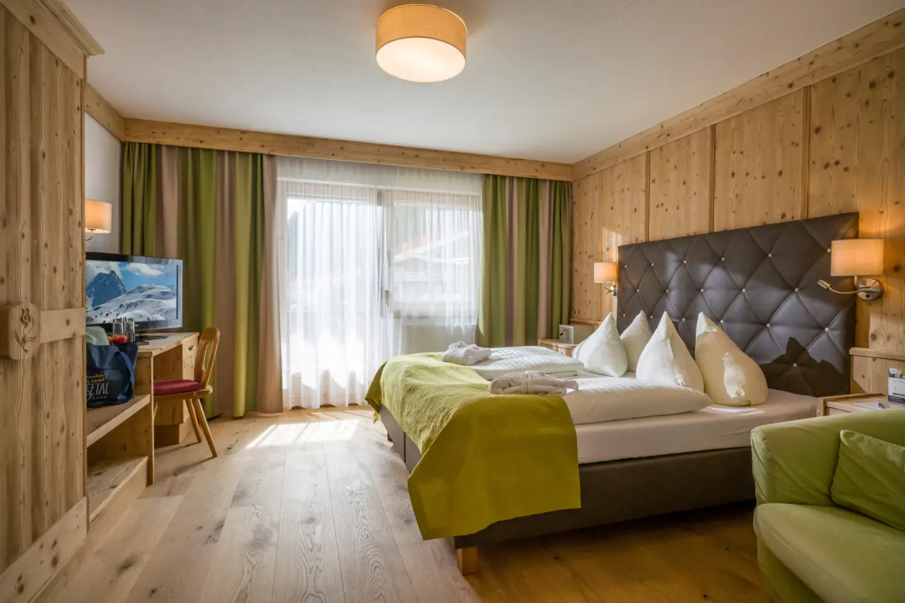 Gemütliches Doppelzimmer im alpinen Stil mit Holzelementen, bequemen Betten und Bademänteln im Alpin Family Resort Seetal.
