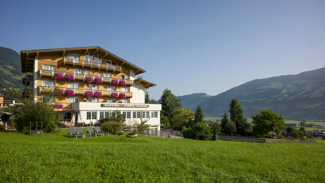 Aussenansicht des Hotel Elisabeth mit blühenden Balkonen und Alpenpanorama im sonnigen Tal.
