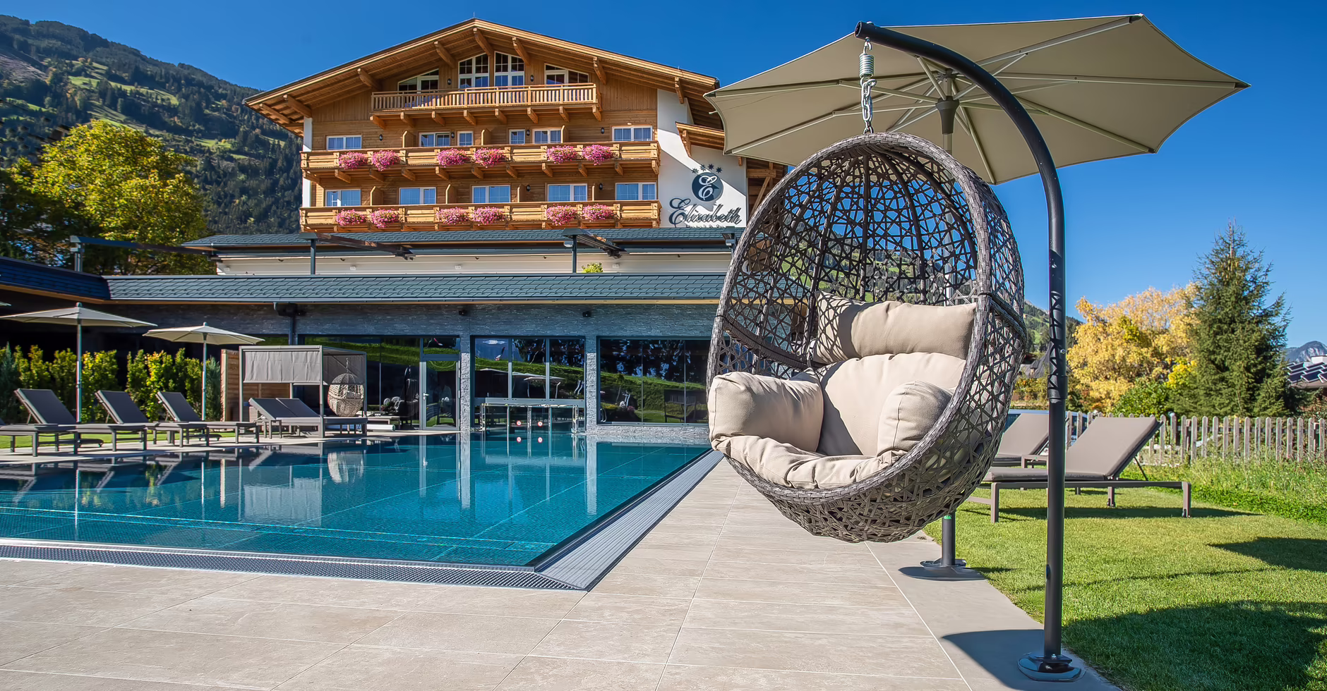 Hotel Elisabeth in Fügen – Außenpool mit Hotelgebäude und Bergkulisse | Wellnesshotel Zillertal