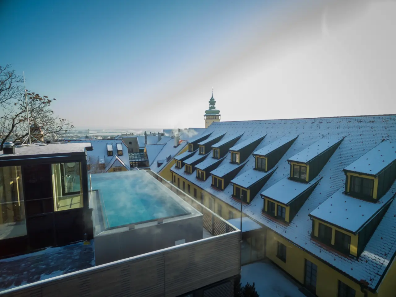 Beheizter Aussenpool mit Dampf im Winter und Blick auf die verschneiten Dächer von Retz im Hotel Althof Retz.