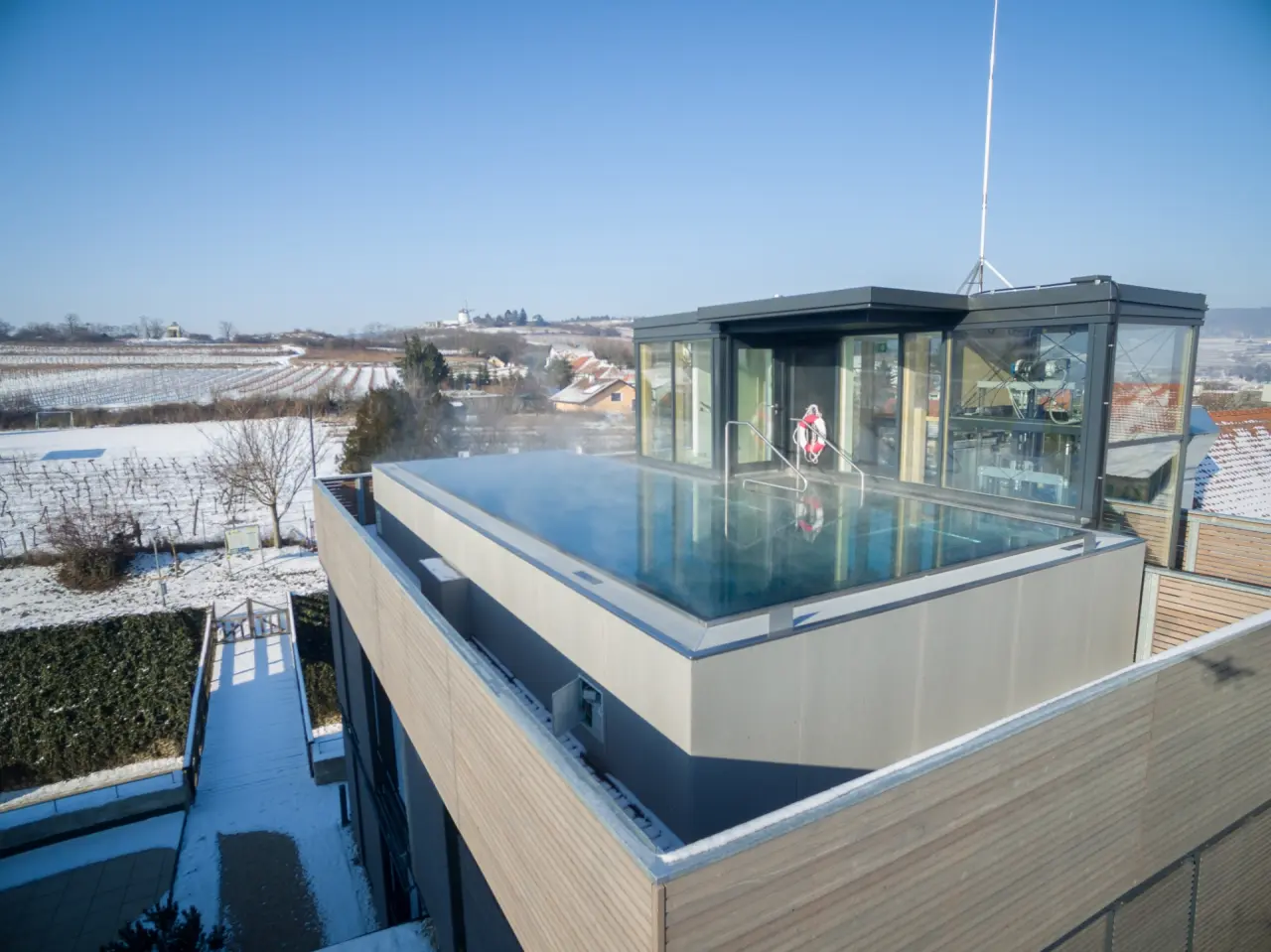 Beheizter Rooftop-Pool mit Dampf und Panoramablick über verschneite Weinberge im Hotel Althof Retz.