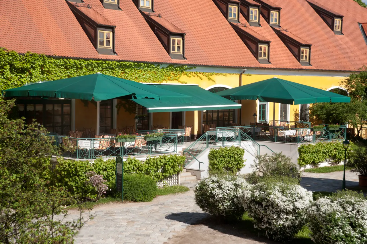 Sonnige Gartenterrasse des Restaurants mit grünen Markisen und Tischen im Hotel Althof Retz.