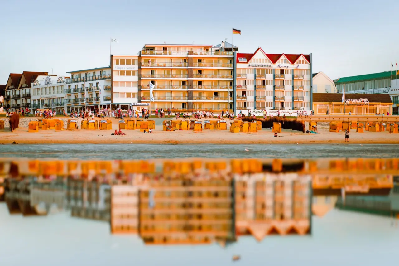 Strandhotel Duhnen mit Strandkörben am Sandstrand bei Sonnenuntergang und Wasserspiegelung