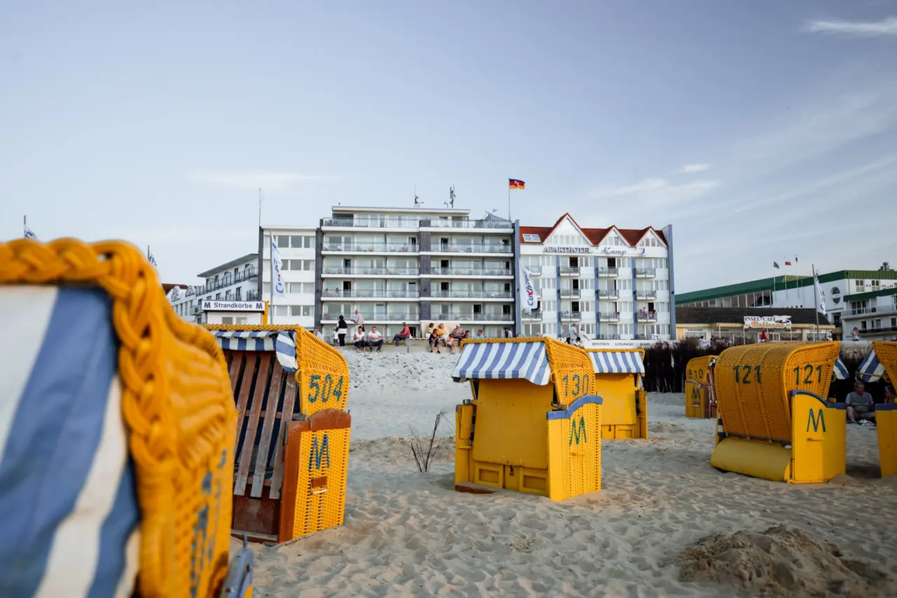 Strandhotel Duhnen direkt am Sandstrand mit gelben Strandkörben und Blick auf die Nordsee.