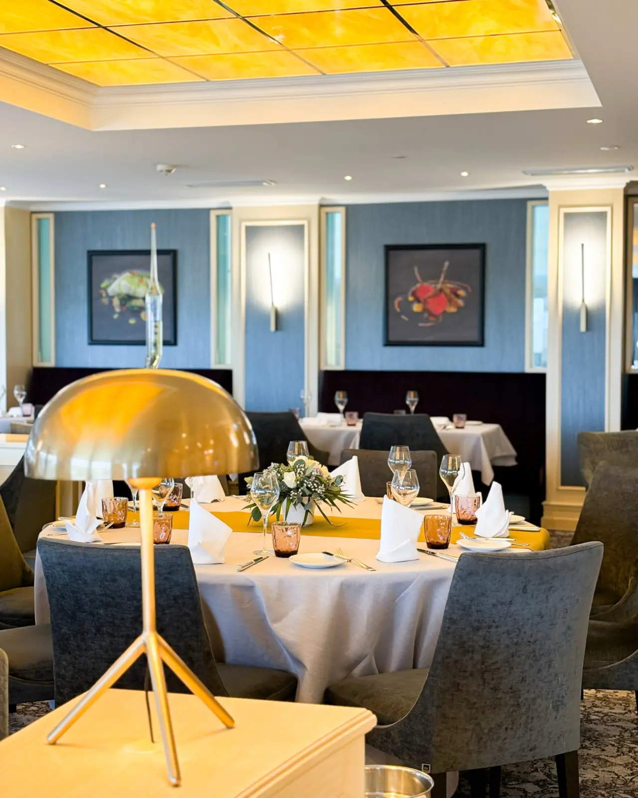 Elegant gedeckter Tisch im Restaurant des Strandhotel Duhnen mit stilvoller Beleuchtung und blauer Wandgestaltung.