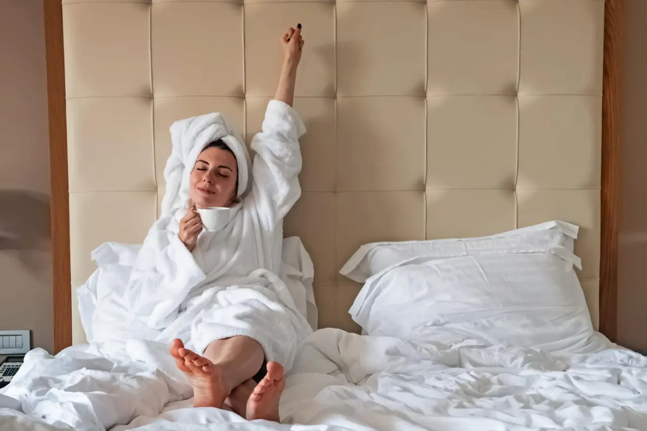 Entspannte Frau im Bademantel mit Kaffee im komfortablen Hotelzimmer des Strandhotel Duhnen.