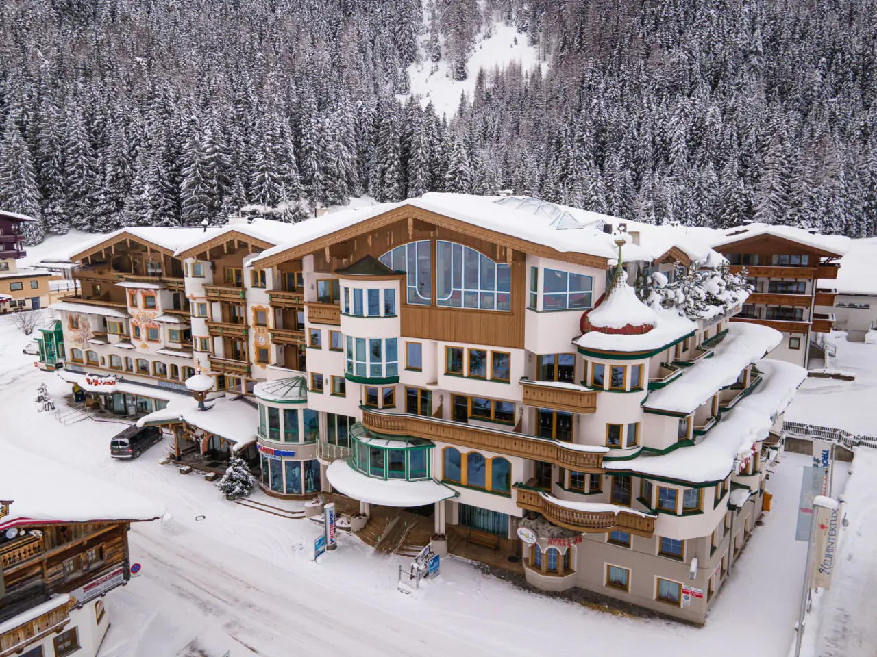 Winterliche Aussenansicht des Hotel Neuhintertux, umgeben von verschneiten Tannenwäldern in den Alpen.