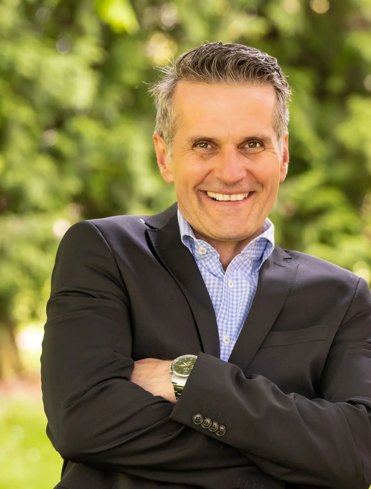 Porträt eines lächelnden Mannes, möglicherweise des Hoteliers, vor grünem Hintergrund im Menschels Vitalresort.