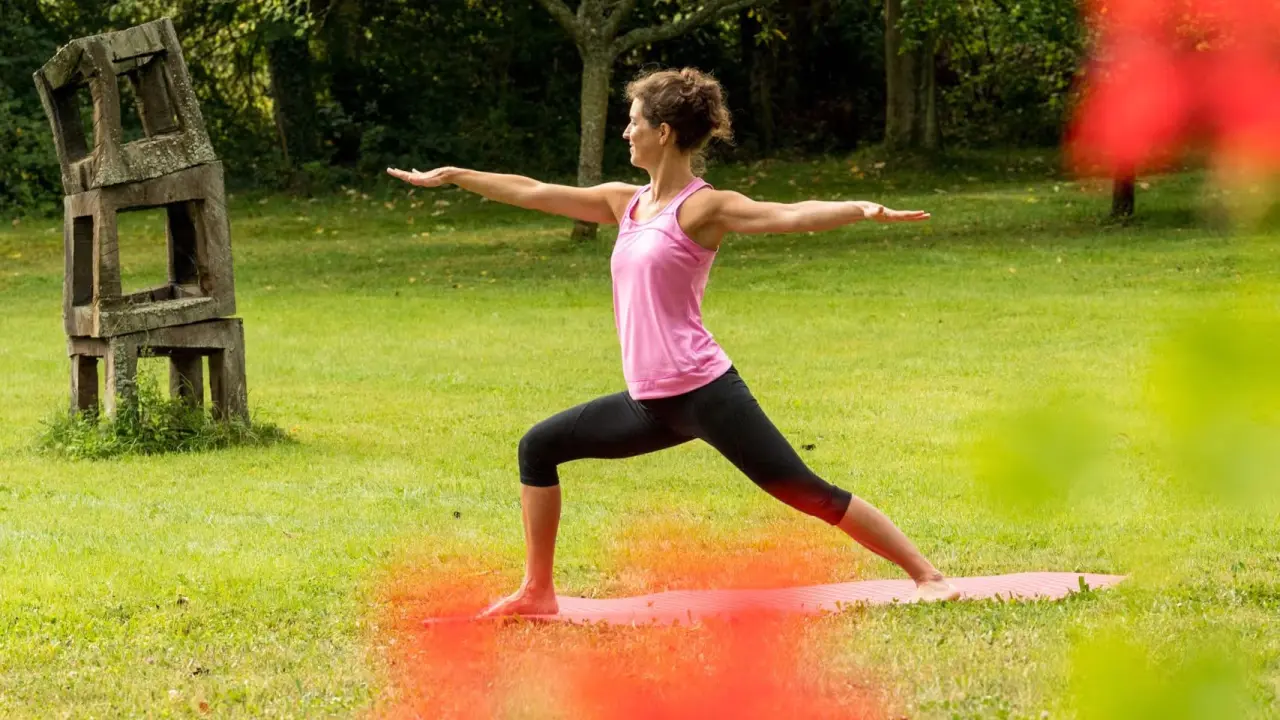 Frau in Yoga-Pose auf Matte im Grünen von Menschels Vitalresort. Outdoor-Fitness und Entspannung.