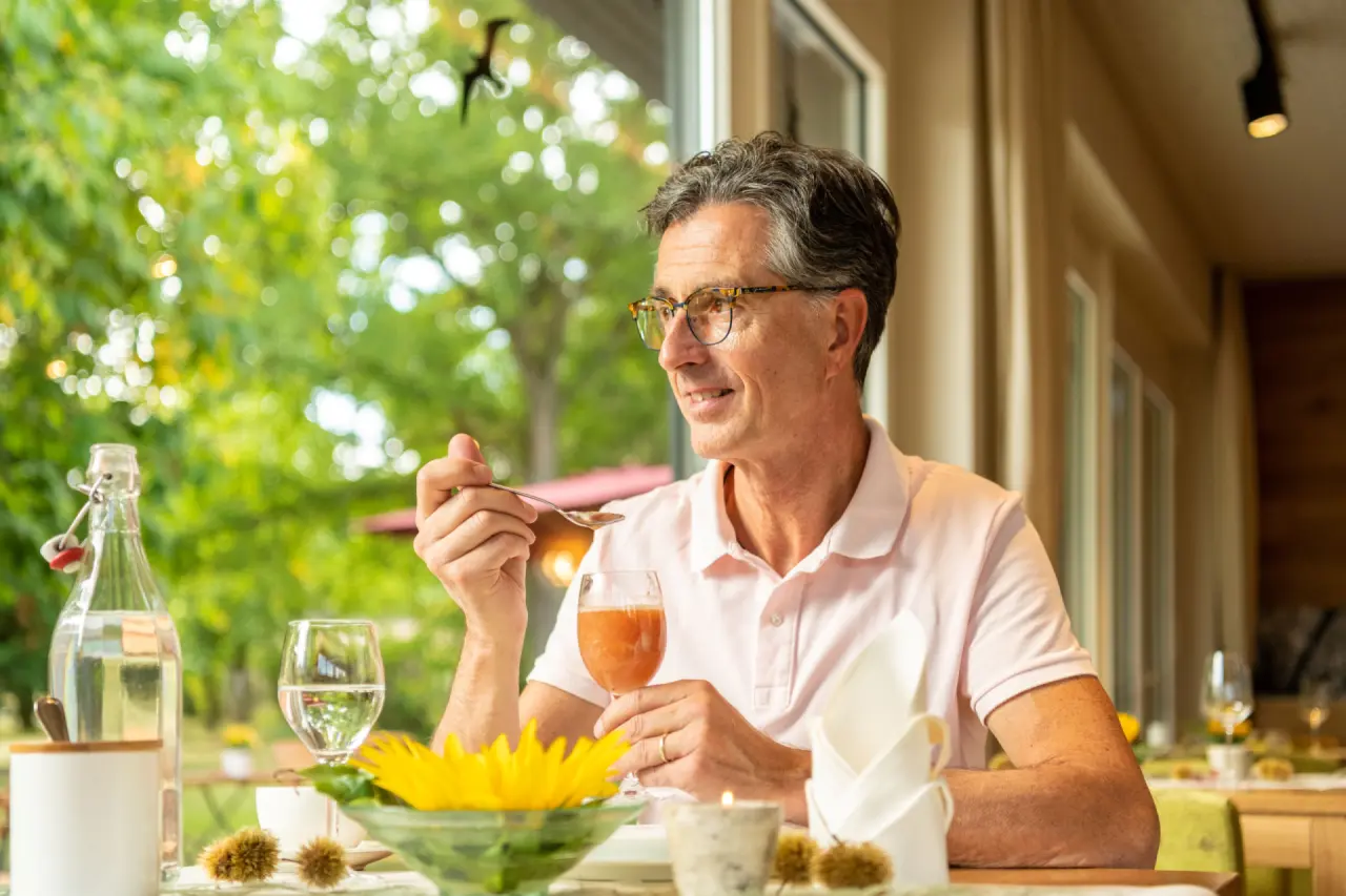 Gast genießt gesundes Frühstück oder Saft im hellen Restaurant mit Gartenblick im Menschels Vitalresort.