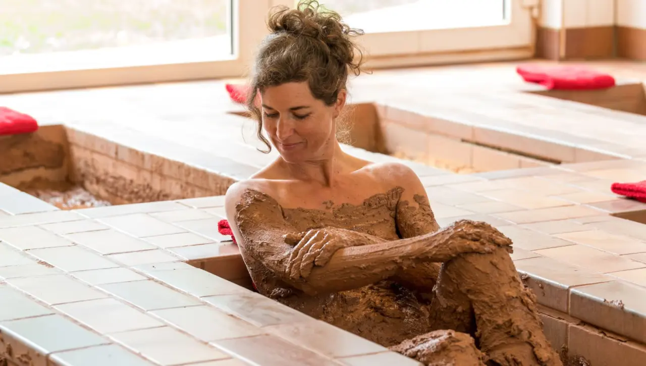 Frau genießt ein entspannendes Schlammbad im Spa-Bereich von Menschels Vitalresort, ideal für Wellness und Erholung.