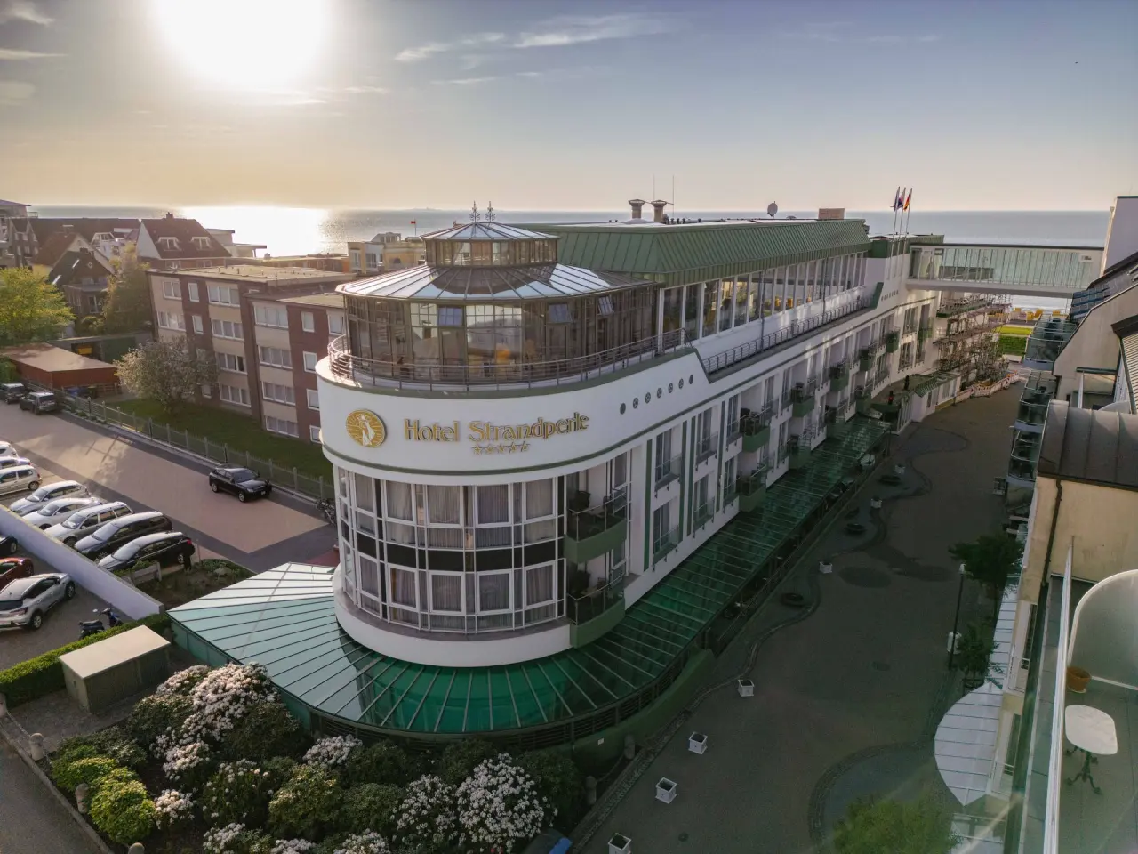 Luftbild des Hotel Strandperle an der Küste bei Sonnenuntergang, mit Blick auf das Meer und die einzigartige Architektur.