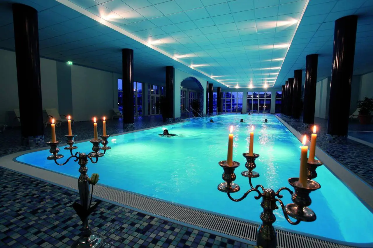 Beheizter Innenpool mit blauer Beleuchtung und Kerzenlicht im Precise Resort Hafendorf Rheinsberg.