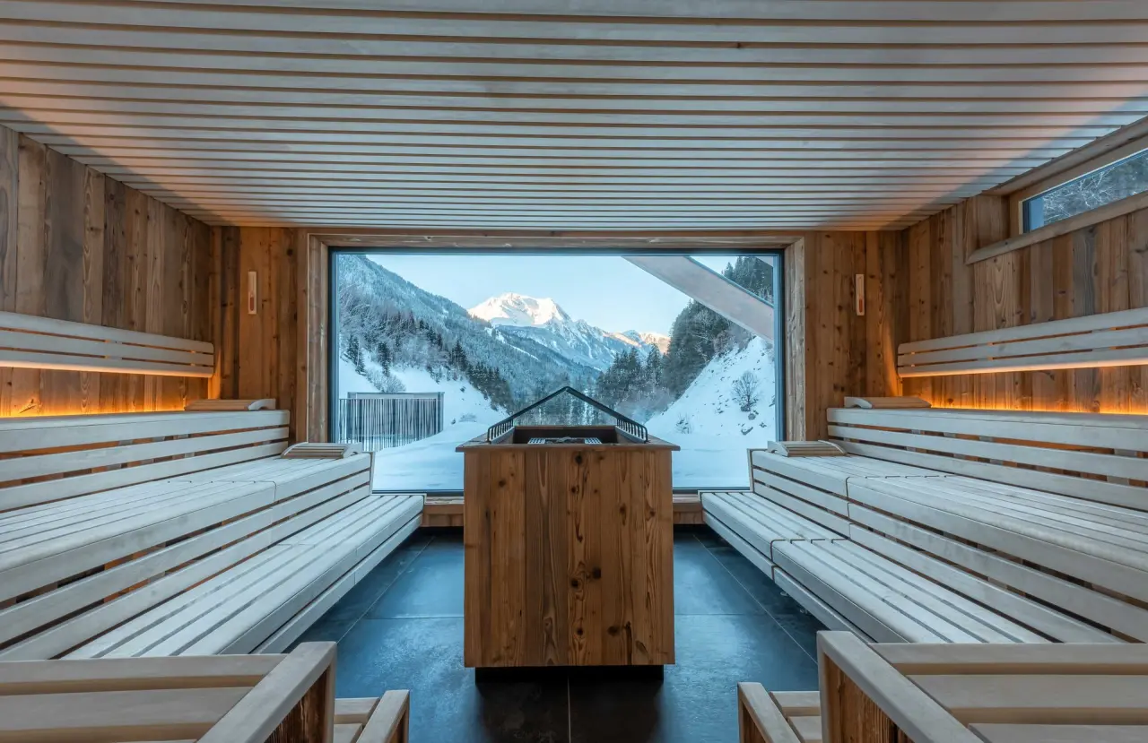 Moderne Panoramasauna mit Blick auf die verschneiten Alpen im ZillergrundRock Luxury Mountain Resort. Wellness mit Aussicht.
