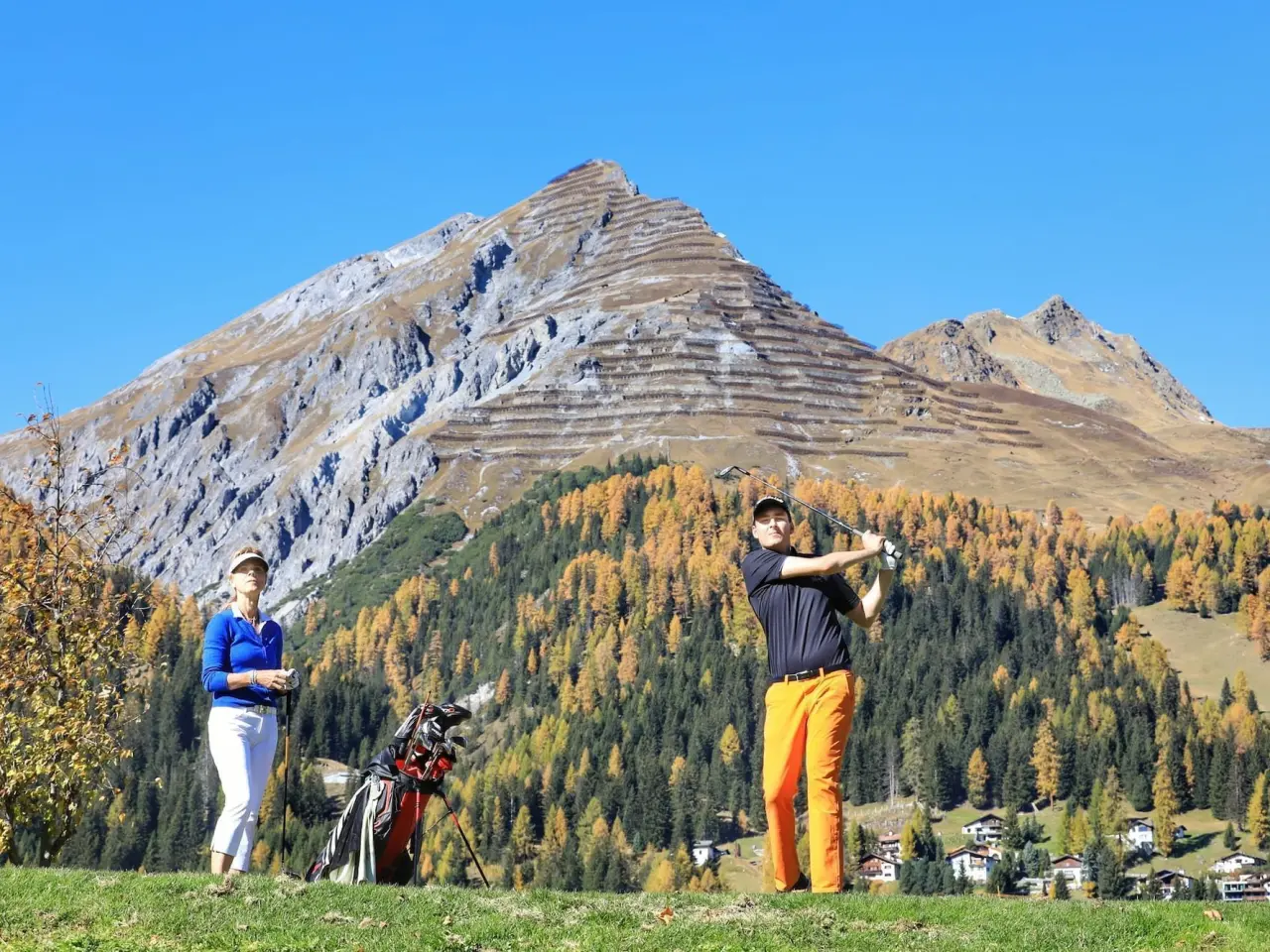 Golfer auf dem Golfplatz mit herbstlicher Bergkulisse bei Davos. Outdoor-Aktivität nahe dem Precise Tale Seehof Davos.