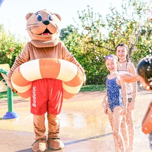 Maskottchen Badolin und lachende Kinder im Wasserspielbereich des Allegria Resort Stegersbach