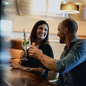 Lachendes Paar genießt Cocktails an der Bar im Allegria Resort Stegersbach.
