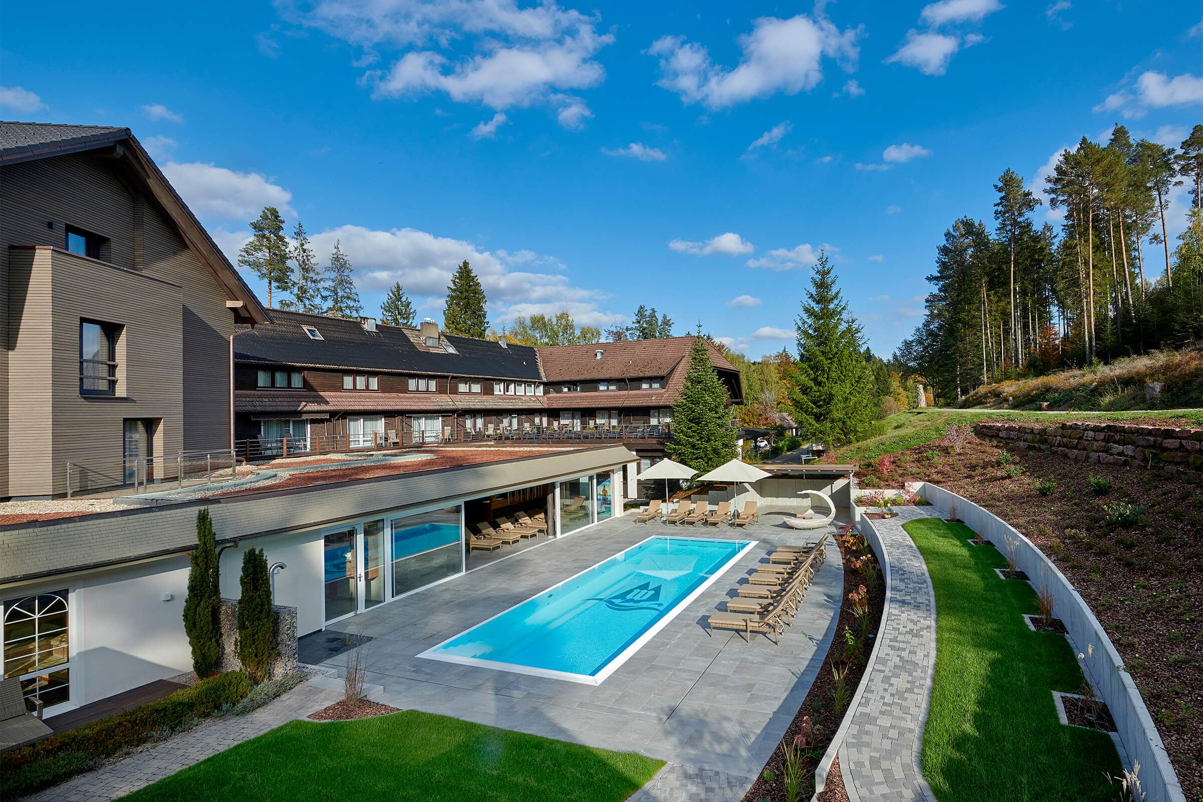 Hotel Waldsägmühle in Pfalzgrafenweiler-Kälberbronn – Außenansicht mit großem Poolbereich | Wellnesshotel Schwarzwald