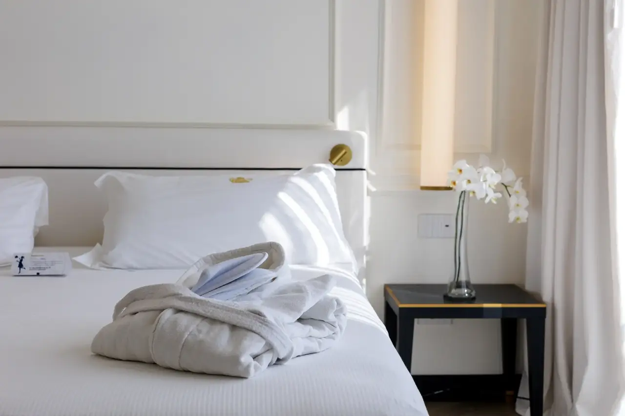 Hotel De Londres in Rimini – Elegantes Hotelbett mit weißem Bademantel und Orchideen | Wellnesshotel Adriaküste