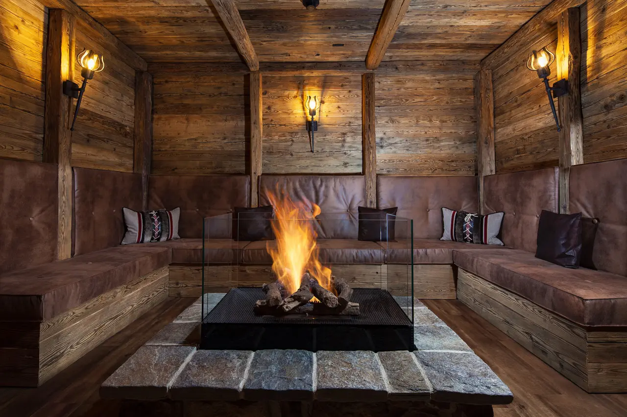 Gemütliche Kaminlounge im alpinen Stil mit Ledersitzbänken im Alm- & Wellnesshotel Alpenhof.