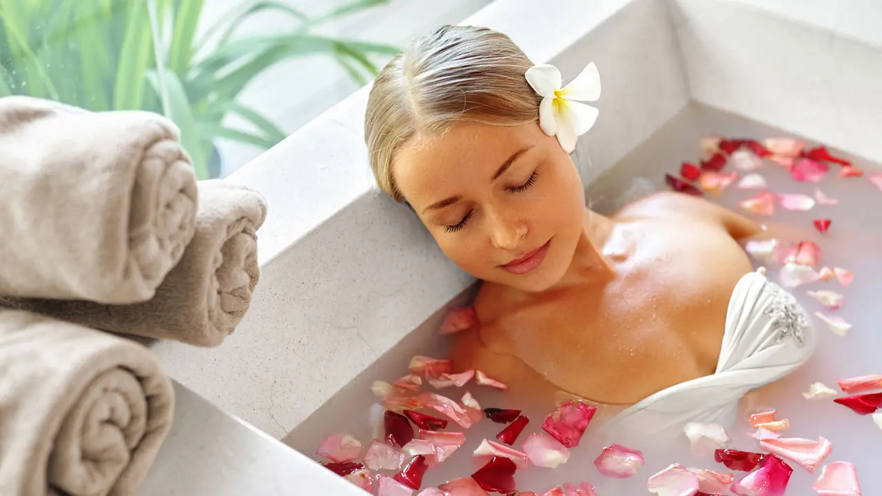 Frau entspannt in einem Rosenblütenbad im Spa-Bereich des Alm- & Wellnesshotel Alpenhof.