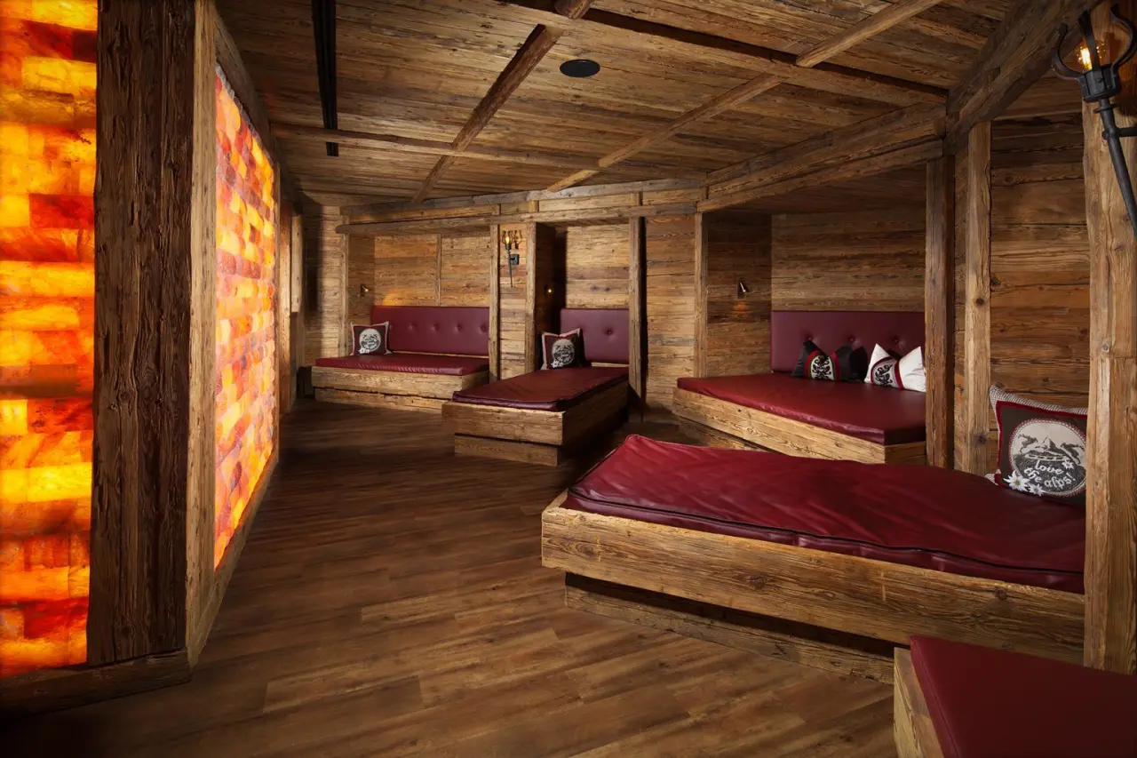 Entspannungsraum mit beleuchteter Salzwand und gemütlichen Holzliegen im Alm- & Wellnesshotel Alpenhof.