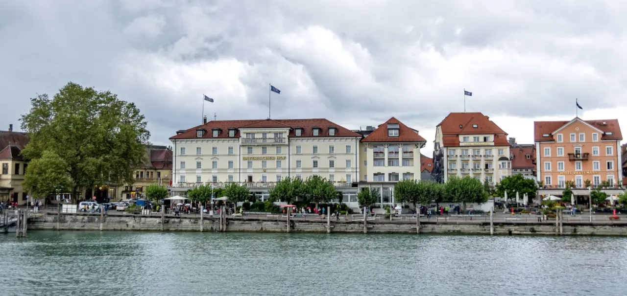 Aussenansicht des Hotel Bayrischer Hof am Seeufer in Lindau mit Promenade und bewölktem Himmel.